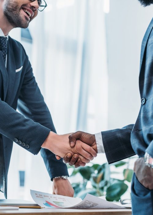 cropped image of smiling multicultural businessmen shaking hands in office