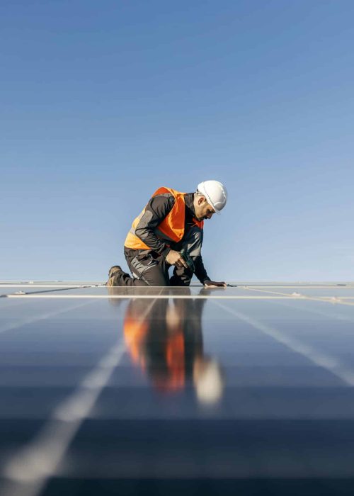 A handyman on the rooftop installing solar panels.